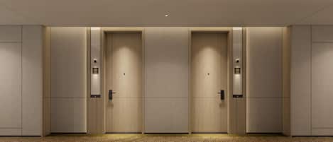 Cuatro puertas idénticas en fila, cada una con una pantalla digital arriba, ubicadas en un interior moderno con piso alfombrado.