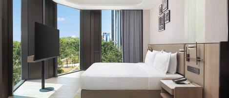 A modern hotel room with a large bed, a flat-screen TV, a bedside table with a remote, and a view of the cityscape.