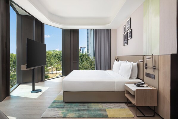 A modern hotel room with a large bed, a flat-screen TV, a bedside table with a remote, and a view of the cityscape.