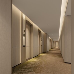 Un largo y estrecho pasillo de hotel con piso alfombrado y puertas a ambos lados.