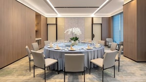 A conference room with a round table, chairs, and a vase of white flowers. - Holiday Inn Shanghai Necc by IHG (Shanghai)