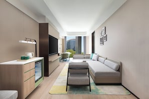 Habitación de hotel moderna con kitchenette, zona de estar y un amplio ventanal con vistas a la ciudad.