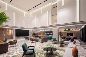 A spacious lobby with a central seating area, a bar, and a large screen.