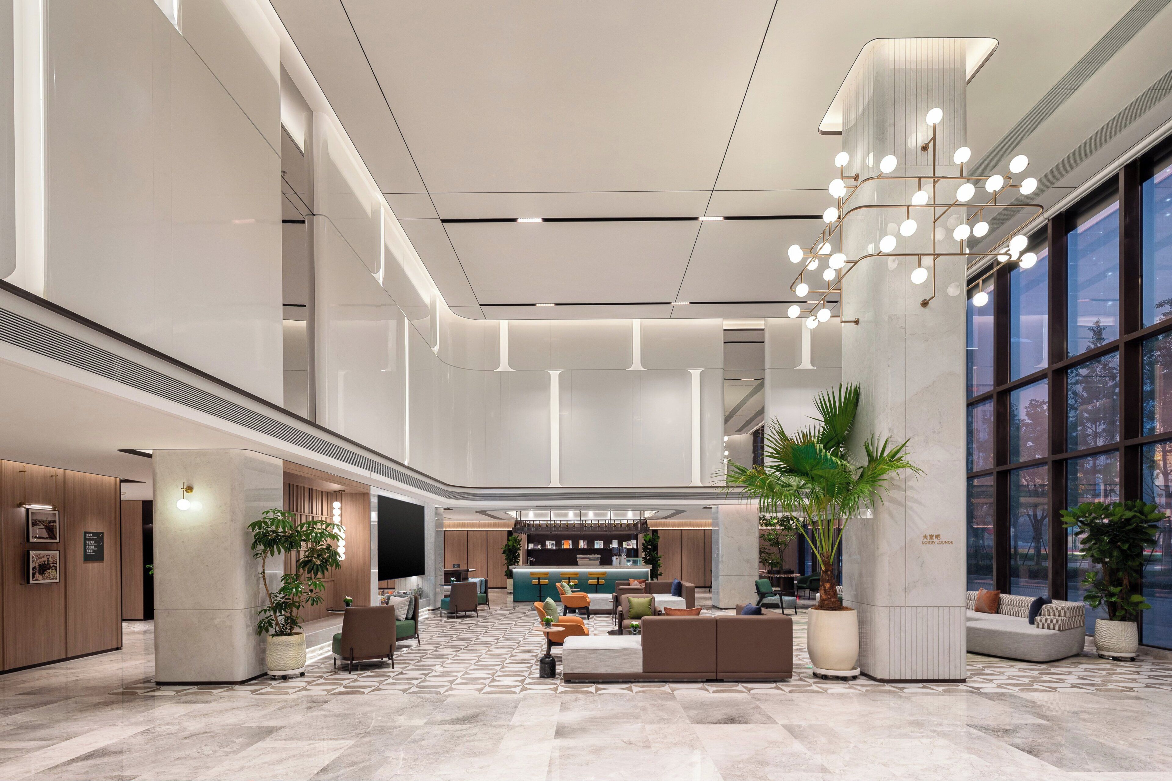 A spacious lobby with a high ceiling, a central seating area, and large windows.