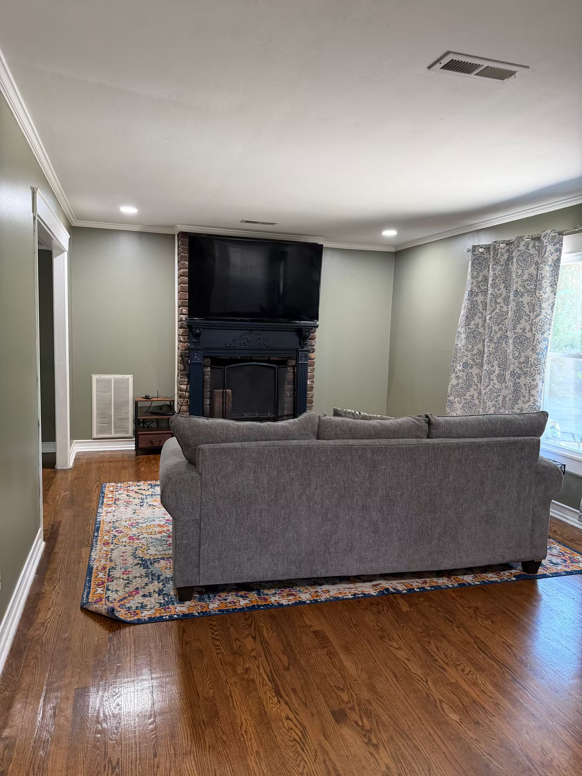 Ein Wohnzimmer mit grauem Sofa, Kamin und Fernseher.