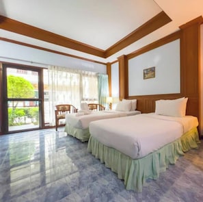 A hotel room with two beds, a chair, a table, and a view through a glass door. - Seaview Resort (Klaeng)