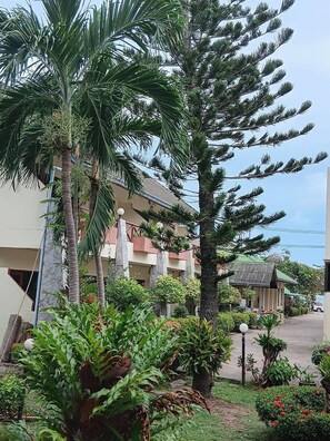 A building with a tiled roof, surrounded by lush greenery and palm trees. - Seaview Resort (Klaeng)