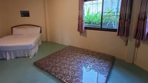 Una habitación con cama, ventana con cortinas, un equipo de aire acondicionado y un cuadro pequeño en la pared.