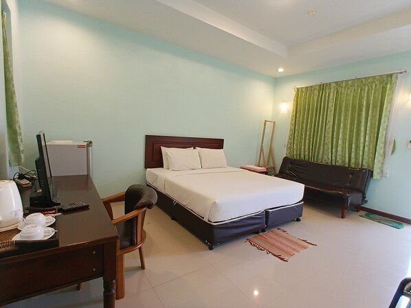 A hotel room with a bed, a desk, a chair, and a mirror. - Seaview Resort (Klaeng)