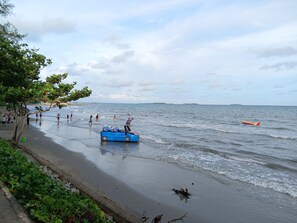 Una playa con gente, un bote inflable azul y una isla distante.