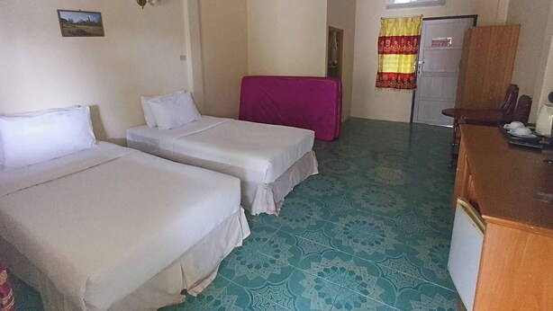 Una habitación con dos camas, un escritorio, una silla, una puerta y un piso estampado.