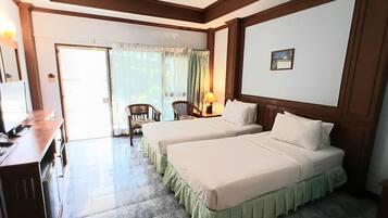 A hotel room with two beds, a desk, a chair, and a view of the outdoors.