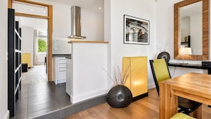 Una cocina moderna con estufa integrada, un comedor con mesa de madera y un espejo grande.