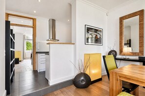 Eine moderne Küche mit Einbauherd, ein Essbereich mit Holztisch und ein großer Spiegel.