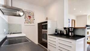 Una cocina moderna con horno empotrado, cafetera y hervidor sobre la encimera.