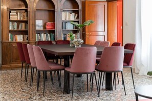 Ein Essbereich mit einem runden Tisch, sechs Stühlen und einem Bücherregal im Hintergrund.