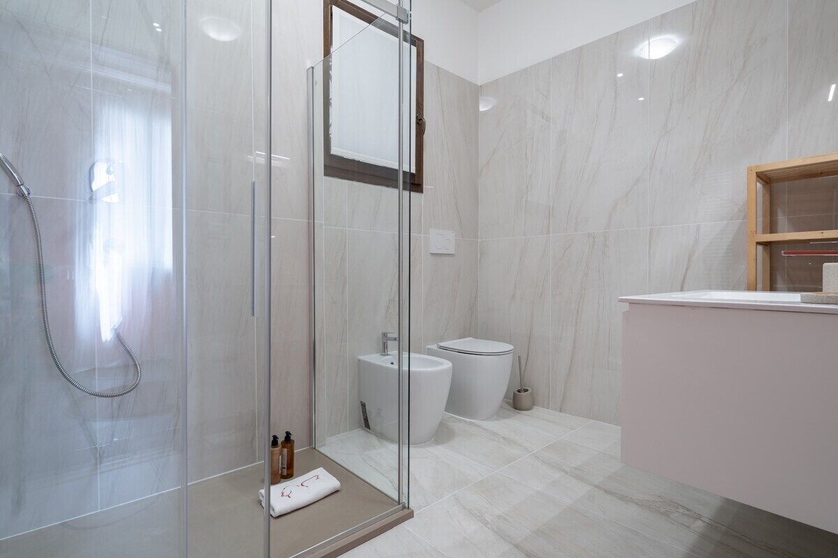 Uma casa de banho moderna com chuveiro em cabine de vidro, lavatório branco e sanita.
