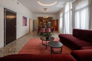 Un saló modern amb un sofà vermell, una taula de centre i una zona de menjador amb un armari de fusta i prestatgeries.