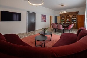 A modern living room with a sofa, a coffee table, and a dining area with chairs and a table. - Venetian Velvet (Venice)