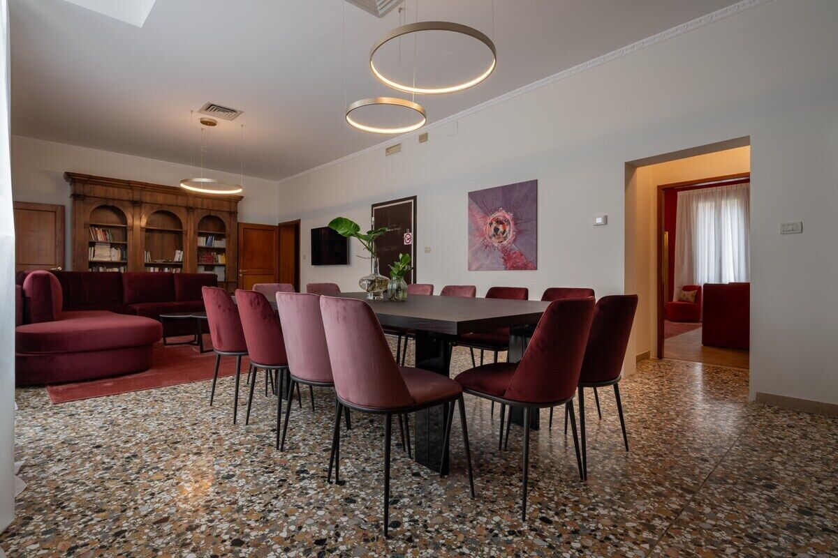 A modern dining area with a round table and chairs, a bookshelf, and a painting on the wall.