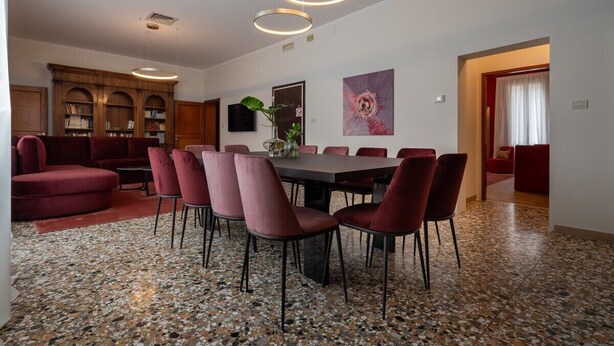 Uma sala de jantar moderna com uma mesa redonda e cadeiras, uma estante de livros e um quadro na parede.