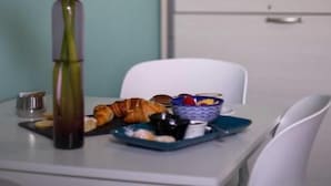 Uma mesa de jantar com um vaso de flores, um prato de comida e uma cadeira branca.
