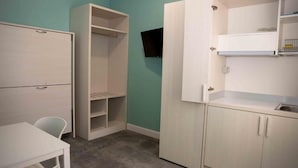 Quarto compacto com cozinha compacta, uma mesa branca e uma cadeira.
