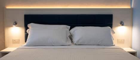 Una habitación de hotel con cama, dos lámparas de noche y cabecero.