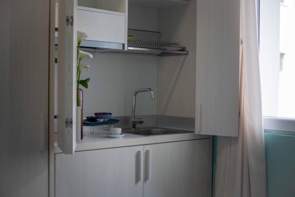 Eine kleine Küchenzeile mit integriertem Spülbecken, einer Arbeitsplatte und einem Schrank.