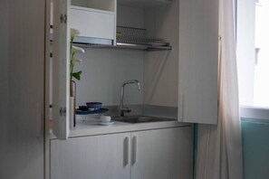 A compact kitchenette with a built-in sink, a small countertop, and a cabinet.