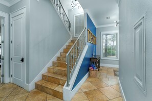 Eine Treppe mit blauer Akzentwand, eine Tür mit Zahlenschloss und ein Korb mit zusammengelegten Gegenständen auf dem Boden.