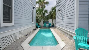 A rectangular pool with a white border, surrounded by a paved patio. - Sandy Heels | Steps to the Beach | Pool | Pet Friendly (Destin)