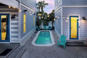 A pool area with a rectangular pool, two doors with yellow windows, and a sign that says 'Enjoy'. - Sandy Heels | 6BR Crystal Beach Home with Gulf Views, Private Pool & Steps to Beach | Sleeps 20 (Destin)