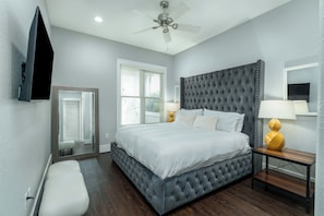 A bedroom with a large bed, a ceiling fan, a bedside table with a lamp, and a mirror on the wall. - Sandy Heels | 6BR Crystal Beach Home with Gulf Views, Private Pool & Steps to Beach | Sleeps 20 (Destin)