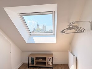 Quarto com claraboia, prateleira de madeira e radiador.