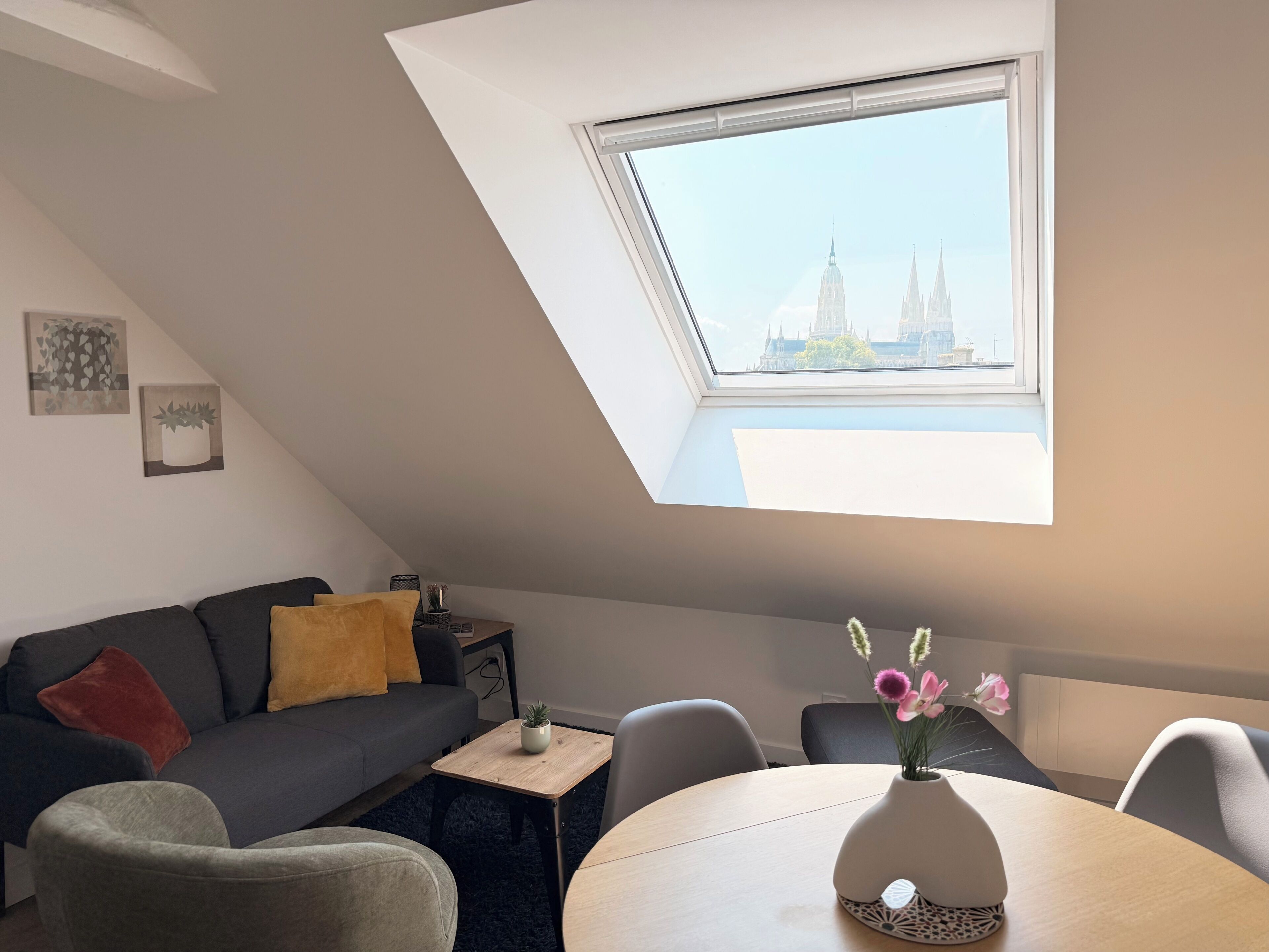 A modern loft bedroom with a skylight, a dining area, and a view of a historic building.