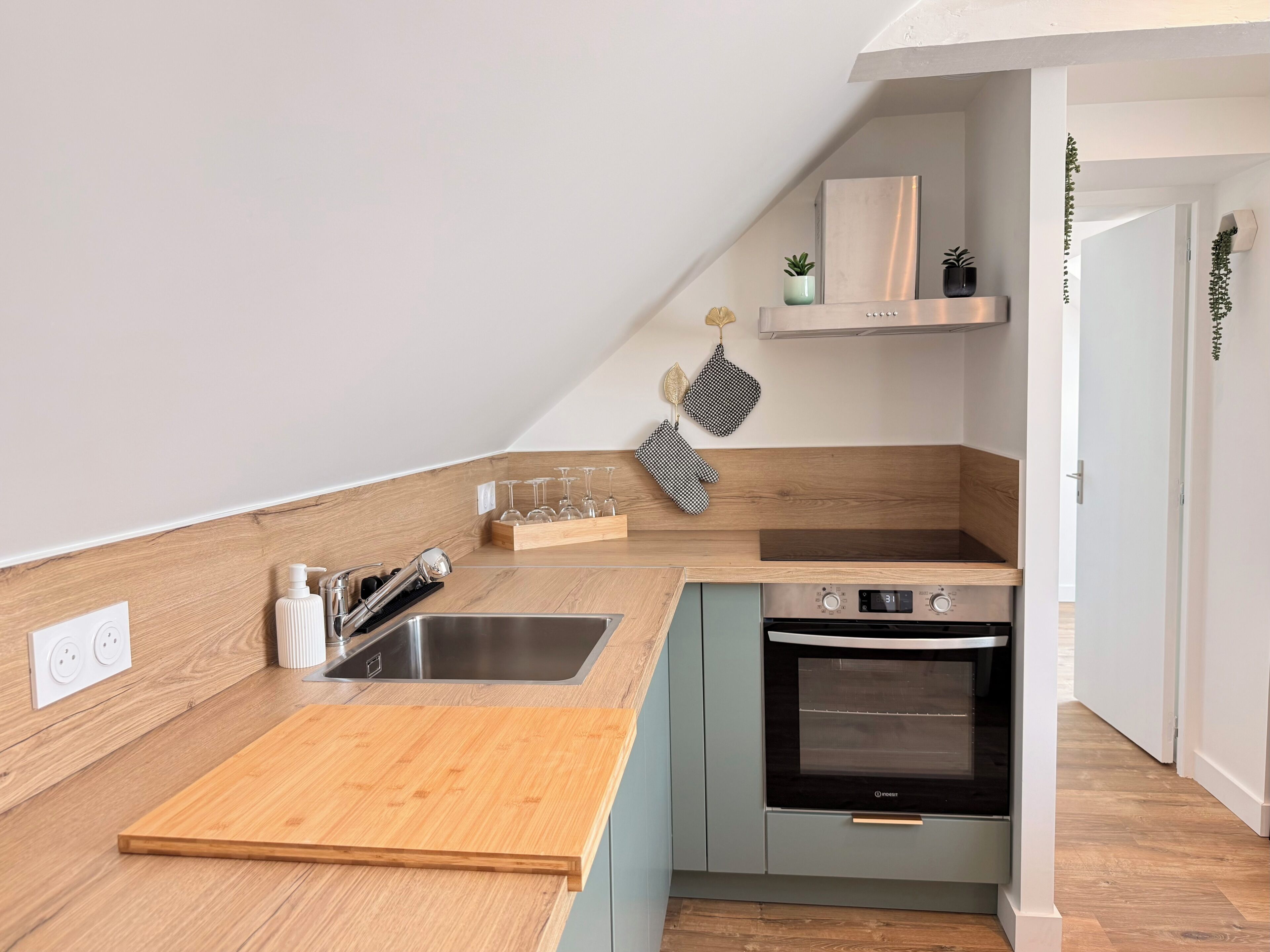A compact kitchen with a wooden countertop, stainless steel sink, and a built-in oven.