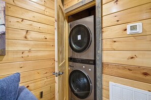 A wooden interior with a double-door laundry room, a thermostat, and a vent. - Smoky Ridge Retreat | 2 Cabins, Views & Games (Sevierville)