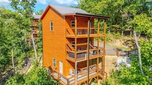 Een houten vakantiehuis met meerdere verdiepingen en balkons, omringd door bomen.