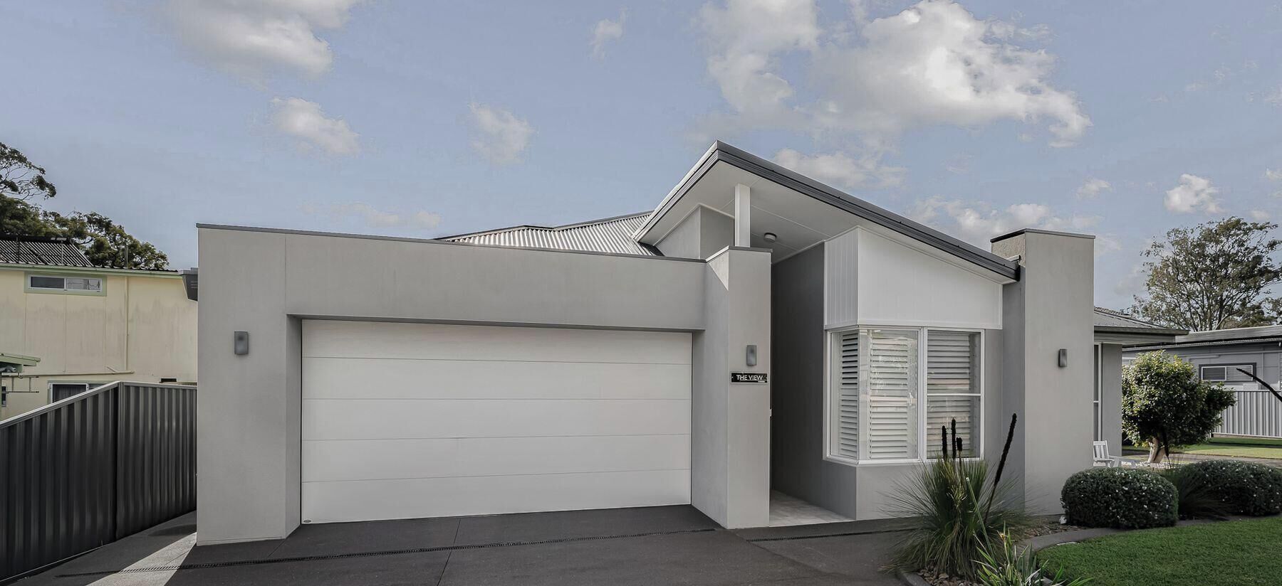 A modern two-story house with a garage, a covered porch, and a well-maintained lawn.