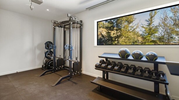 A gym with a squat rack, weight plates, and dumbbells.