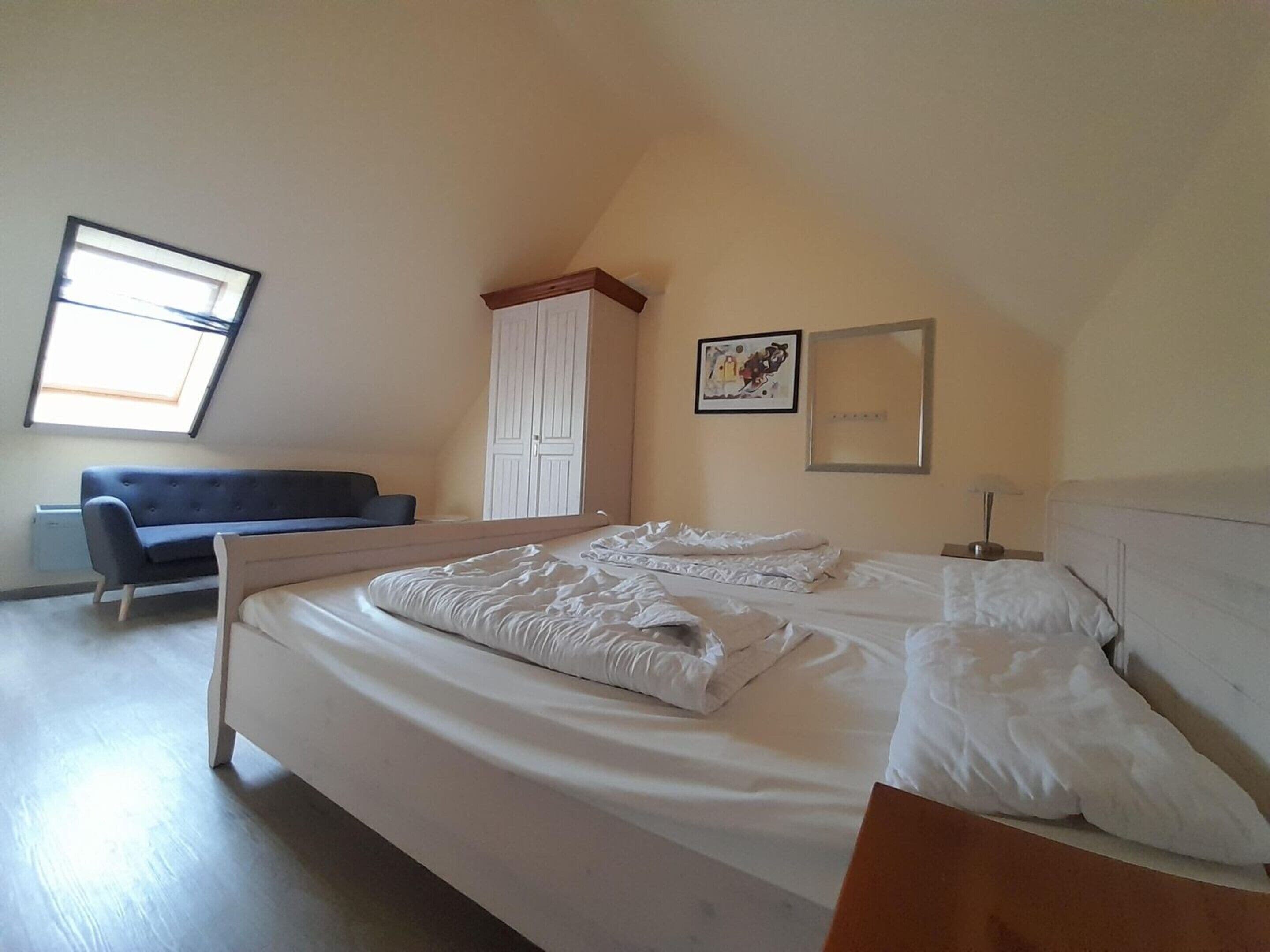 Um quarto com cama, sofá, guarda-roupa e janela.