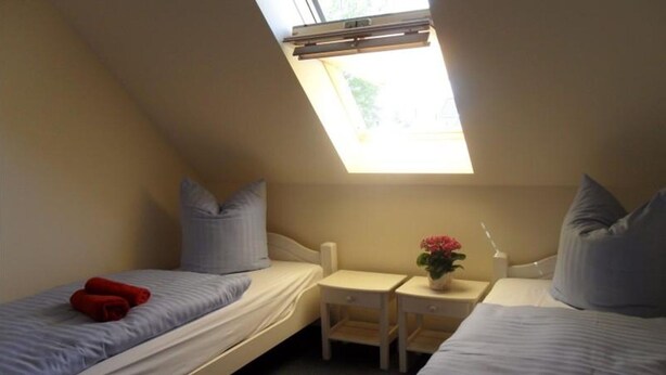 A small, single-room accommodation with two beds, a small table, and a window. - Gemutliches Ferienhaus mit Terrasse Nahe dem Muritzsee in Rechlin (Rechlin)