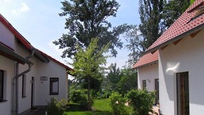 A courtyard with two buildings, a grassy area, and trees. - Gemutliches Ferienhaus mit Terrasse Nahe dem Muritzsee in Rechlin (Rechlin)