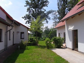A courtyard with two buildings, a grassy area, and trees. - Gemutliches Ferienhaus mit Terrasse Nahe dem Muritzsee in Rechlin (Rechlin)