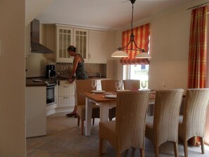A kitchen with a dining area, including a table with chairs and a hanging light fixture. - Gemutliches Ferienhaus mit Terrasse Nahe dem Muritzsee in Rechlin (Rechlin)