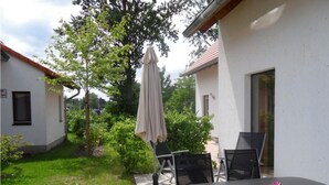 An outdoor patio with a table and chairs, a covered umbrella, and a small garden area. - Gemutliches Ferienhaus mit Terrasse Nahe dem Muritzsee in Rechlin (Rechlin)
