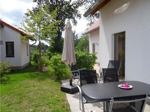 An outdoor patio with a table and chairs, a covered umbrella, and a small garden area. - Gemutliches Ferienhaus mit Terrasse Nahe dem Muritzsee in Rechlin (Rechlin)