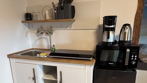 Une cuisine compacte équipée d’un évier, d’un four à micro-ondes, d’une machine à café et d’un réfrigérateur.