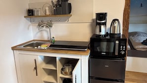 Une cuisine compacte équipée d’un évier, d’une machine à café, d’un four à micro-ondes et d’un réfrigérateur.